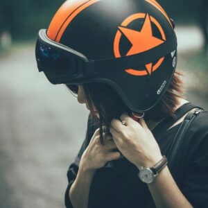 A woman adjusting a safety helmet on an outdoor road, emphasizing protective gear.